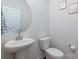 Elegant powder room featuring a pedestal sink, round mirror, and modern fixtures at 504 Cranford Dr, Pineville, NC 28134