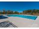 Outdoor swimming pool area with clear blue water, and a paved deck, surrounded by mature trees at 504 Cranford Dr, Pineville, NC 28134