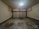 Empty two car garage with concrete floor, white garage door and unfinished walls at 5416 River Falls Dr, Charlotte, NC 28215