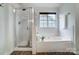 Bright primary bathroom featuring a glass enclosed shower, soaking tub, and tiled flooring at 6519 Summertree Ln, Charlotte, NC 28270