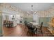 Open dining room with wood floors, floral wallpaper, and a view to the kitchen at 6807 Stoney Ridge Rd, Matthews, NC 28104