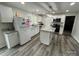 Bright kitchen featuring a center island, white cabinets, stainless steel appliances, and modern gray wood flooring at 8124 Wood St, Mount Pleasant, NC 28124