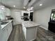 Bright kitchen featuring a center island, white cabinets, stainless steel appliances, and modern gray wood flooring at 8124 Wood St, Mount Pleasant, NC 28124