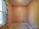 This bedroom features neutral carpeting, peach-painted walls, and a window dressed with a floral curtain at 940 Brittany Ct # 23, Gastonia, NC 28056