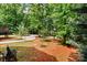 Lush backyard with mature trees, walkways, and vibrant red dirt provides a serene and natural setting at 9506 Minnie Lemmond Ln # 170, Mint Hill, NC 28227