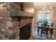 Close-up of a stone fireplace with a wood mantel and view to an eat-in kitchen with wood table and blue accents at 9820 Janeiro Dr, Huntersville, NC 28078
