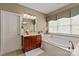 Bathroom with cherry vanity, tiled floor, soaking tub, and natural light from window for a relaxing atmosphere at 11308 Wheat Ridge Rd, Charlotte, NC 28277