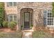 Elegant front door framed by stone, complemented by black shutters and lush greenery at 11308 Wheat Ridge Rd, Charlotte, NC 28277