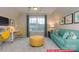 Comfortable bonus room featuring a turquoise sofa, yellow ottoman, and bright window at 122 Fordingbridge Ln, Mooresville, NC 28115