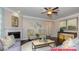 Cozy living room with fireplace, ceiling fan, hardwood floors, and neutral decor with natural light at 122 Fordingbridge Ln, Mooresville, NC 28115