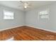 This bedroom has wood floors, neutral walls, base molding, two windows, and a ceiling fan at 12300 Eva St, Matthews, NC 28105