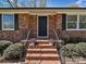 Inviting brick entryway with decorative black door, accented by potted flowers and classic black railings at 12300 Eva St, Matthews, NC 28105