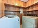 This laundry room has wood paneling, shelving, tile flooring, a new white washing machine, and an old dryer at 12300 Eva St, Matthews, NC 28105