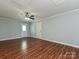 Spacious living room with wood flooring, ceiling fan, neutral walls, and two doors at 12300 Eva St, Matthews, NC 28105