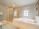 Bright bathroom featuring a glass shower and a large soaking tub with brass fixtures at 1529 S Wendover Rd, Charlotte, NC 28211
