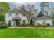 Charming two-story home with white brick, green shutters, mature trees, and a lush, landscaped front yard at 1529 S Wendover Rd, Charlotte, NC 28211