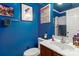 Bright blue bathroom featuring a modern vanity, toilet, and decorative superhero wall art at 16614 Ruby Hill Pl, Charlotte, NC 28278