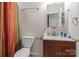 A functional bathroom with a toilet, vanity, sink, mirror and a shower with a colorful curtain at 16614 Ruby Hill Pl, Charlotte, NC 28278