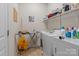 Efficient laundry room with washer, dryer, ironing board, and shelving for ample storage at 16614 Ruby Hill Pl, Charlotte, NC 28278