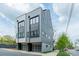 Contemporary townhome featuring a gray exterior, glass-paneled garage doors, and well-maintained curb appeal at 1933 W Trade St, Charlotte, NC 28216