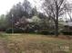 Open yard with mature trees, green grass and colorful spring flowering trees in the background at 235 John Rainey Rd, Salisbury, NC 28147