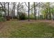 Large grassy backyard with mature trees surrounded by a wood and chain link fence at 2408 Dora Dr, Charlotte, NC 28215