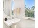 Modern powder room featuring a pedestal sink, sleek fixtures, and a large window with a wooded view at 2504 Park Rose Ln # 18, Charlotte, NC 28204