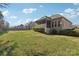 Spacious backyard with lush green grass, a brick house, and a screened-in porch for outdoor relaxation at 304 Wintergreen Ct, Kings Mountain, NC 28086