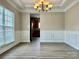 Elegant dining room featuring classic wainscoting, a modern chandelier, and wood-look flooring at 6008 Grassy Knoll Cir, Matthews, NC 28104