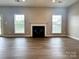 A spacious living room with a fireplace and views of the yard through two bright windows at 6008 Grassy Knoll Cir, Matthews, NC 28104