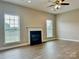 Spacious living room featuring a ceiling fan, fireplace, and natural light from two windows at 6008 Grassy Knoll Cir, Matthews, NC 28104
