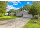 Attractive gray home featuring an attached two-car garage, a long driveway, a bright green lawn, and mature trees at 6741 Stillmeadow Dr, Charlotte, NC 28277