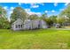 Charming gray house featuring a stone accent wall, green lawn, and mature trees under a bright sky at 6741 Stillmeadow Dr, Charlotte, NC 28277