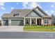 Charming single-story home with a well-manicured lawn, covered porch, and a mix of stone and siding facade at 7130 Irongate Dr, Indian Land, SC 29707