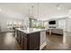 Modern kitchen island with a white countertop, dark cabinetry, and an open view into the adjacent living room at 7130 Irongate Dr, Indian Land, SC 29707