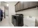 A laundry room with black washer and dryer, overhead cabinets, and a utility sink at 7130 Irongate Dr, Indian Land, SC 29707