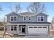 Charming two-story home featuring a two-car garage with a black front door and light blue siding, set against a backdrop of trees at 8007 Willhill Rd, Mint Hill, NC 28227