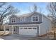 Two-story home featuring a two-car garage with brick accents and a light blue exterior, set against a backdrop of trees at 8007 Willhill Rd, Mint Hill, NC 28227