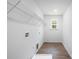 Practical laundry room with white walls, wood-look floor, window, and connections for washer and dryer at 8007 Willhill Rd, Mint Hill, NC 28227