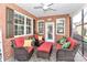 Cozy screened-in patio with brick accents, ceiling fan, and comfortable seating arrangement with red cushions and pillows at 8518 Christalina Ln, Denver, NC 28037