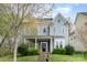 Charming two-story home features a welcoming porch, a well-manicured lawn, and beautiful landscaping at 9832 Sunriver Rd, Huntersville, NC 28078