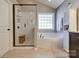 Bright bathroom showcasing a soaking tub, walk-in shower, large window, and natural light at 10728 Bere Island Dr, Charlotte, NC 28278