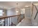 Open upstairs hallway with carpeted floors, decorative lighting, wood banister, and decorative artwork at 10728 Bere Island Dr, Charlotte, NC 28278
