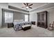 Spacious main bedroom with tray ceiling, two windows, carpeted floors, and an elegant armoire at 10728 Bere Island Dr, Charlotte, NC 28278