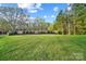 Expansive backyard with lush green grass and a brick wall lined with shrubs, offering privacy and space for recreation at 109 Redbird Ln, Weddington, NC 28104
