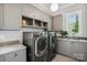 Bright laundry room with gray cabinets, modern washer and dryer set, and a convenient utility sink at 109 Redbird Ln, Weddington, NC 28104