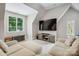 Bright living room with neutral decor, large windows, a modern entertainment center and comfortable seating at 109 Redbird Ln, Weddington, NC 28104
