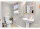 Powder room featuring a pedestal sink, modern toilet, and decorative mirror at 11222 Huntington Meadow Ln, Charlotte, NC 28273