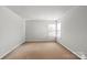 This bedroom features neutral walls, carpet flooring, and a window for natural light at 11415 Serenity Way, Charlotte, NC 28269