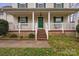 Inviting front porch with white railing, green door and shutters, and brick stairs at 11415 Serenity Way, Charlotte, NC 28269